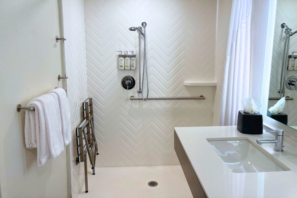 Een moderne badkamer met een douche, een wastafel en een handdoekhouder.