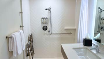 Un baño moderno con ducha, lavamanos y un perchero para toallas.
