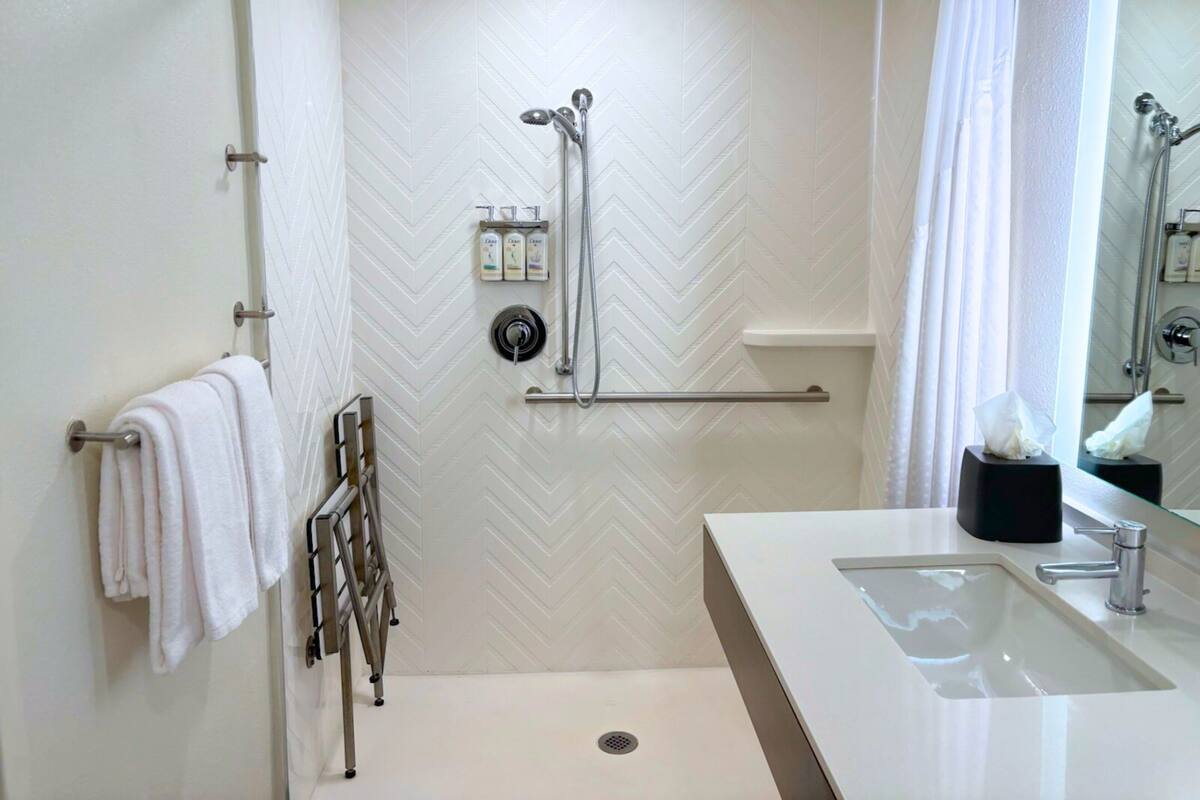 A modern bathroom with a shower, a sink, and a towel rack.