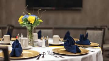 Ein gedeckter Tisch mit Blumen, goldverzerrten Tellern und gefalteten Servietten.