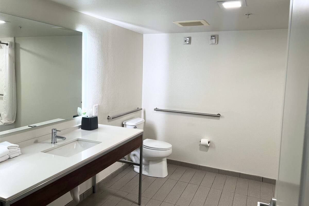 A modern bathroom with a white sink, mirror, and toilet.