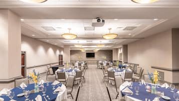 A conference room with round tables, chairs, and a projector screen.