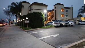A parking lot with cars, a building with multiple floors, and a sign indicating free internet access. - Lambert Inn (Whittier)