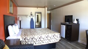 A hotel room with a bed, a desk, a television, and a mini-fridge. - Lambert Inn (Whittier)