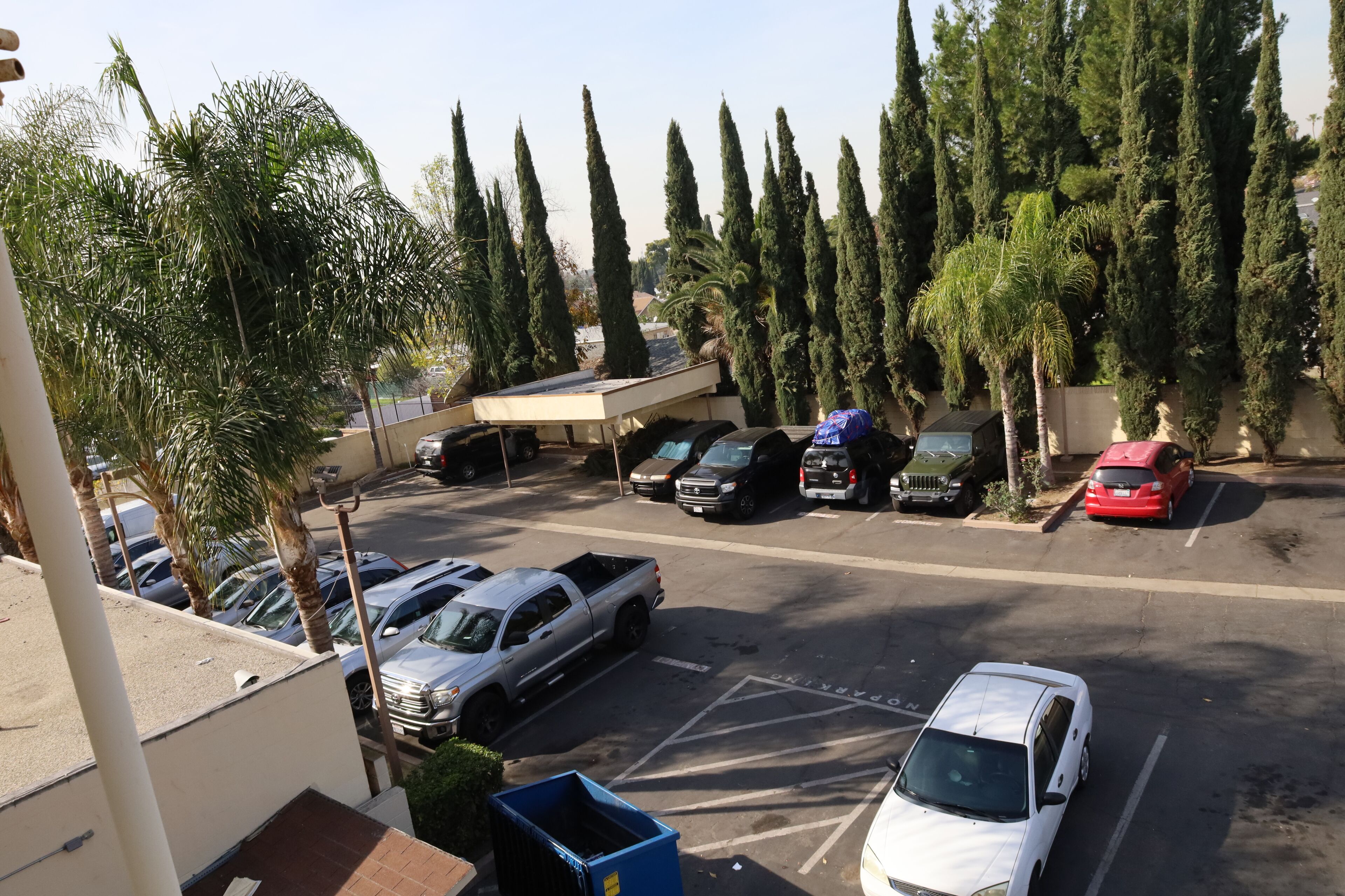A parking lot with several cars and a building in the background.