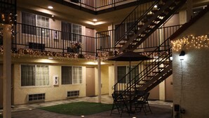 A multi-level outdoor area with a staircase, outdoor seating, and string lights. - Lambert Inn (Whittier)