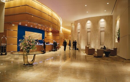 A spacious lobby with a reception desk, a large floral arrangement, and a seating area with sofas and a coffee table.