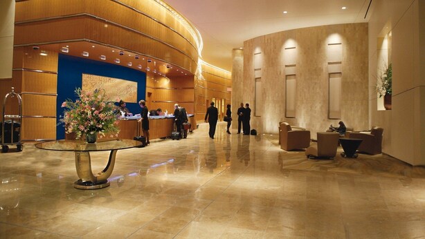 Eine geräumige Lobby mit einer Rezeption, einer großen Blumenkomposition und einer Sitzecke mit Sofas und einem Couchtisch.