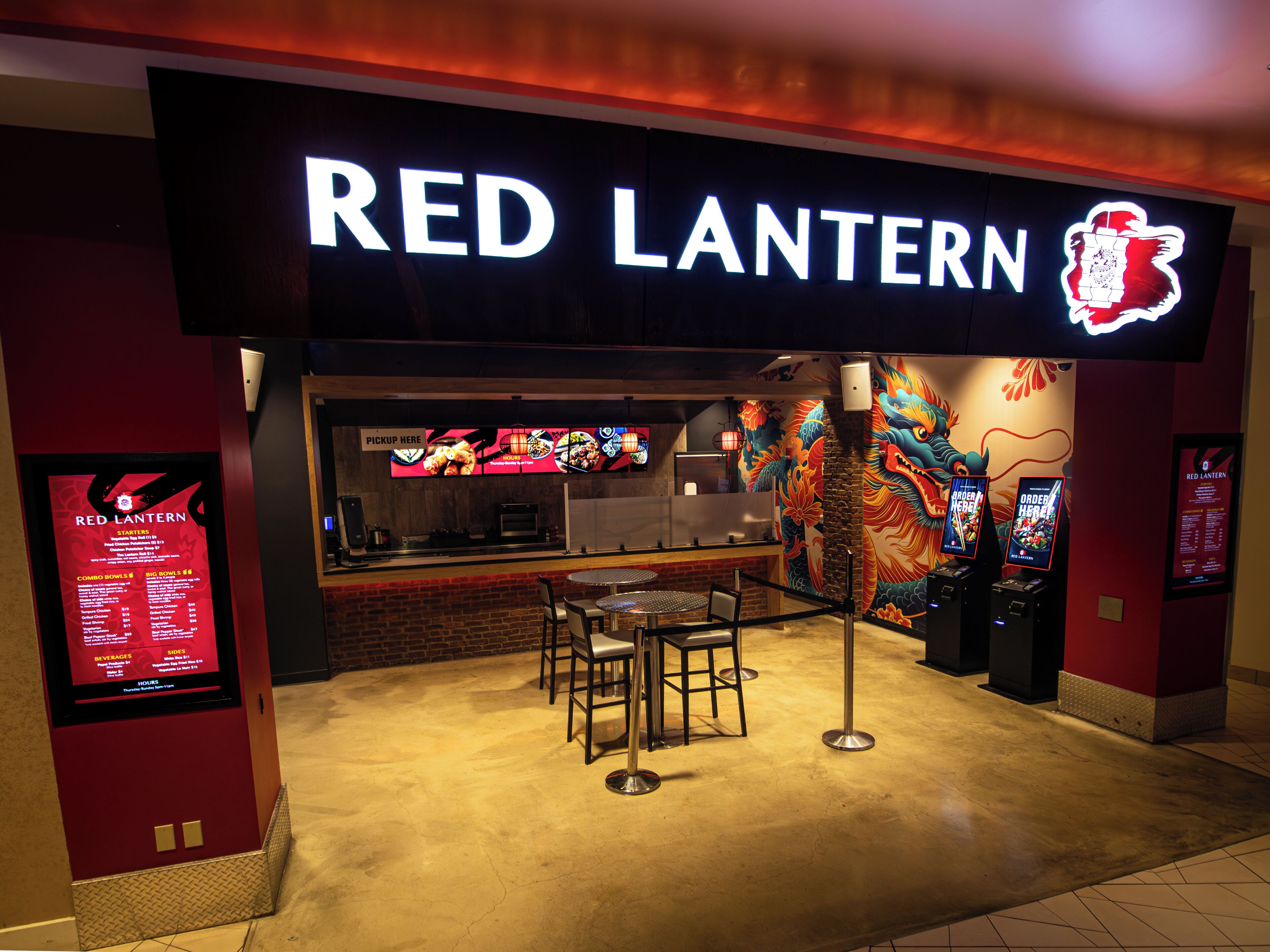 A Red Lantern restaurant with a neon sign, a mural, and a counter with a menu display.