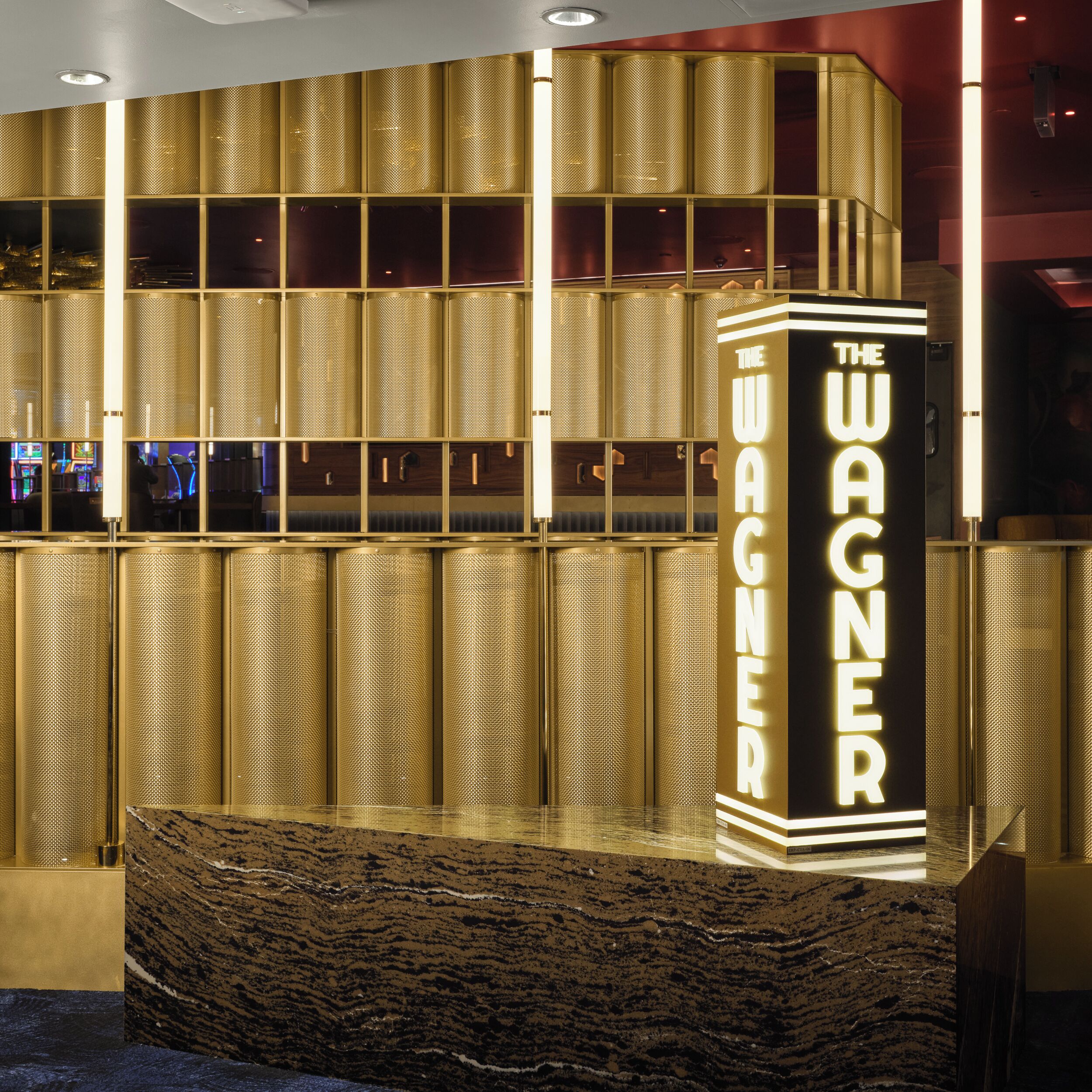 A reception area with a prominent vertical sign reading 'THE WAGNER' and a patterned wall behind it.