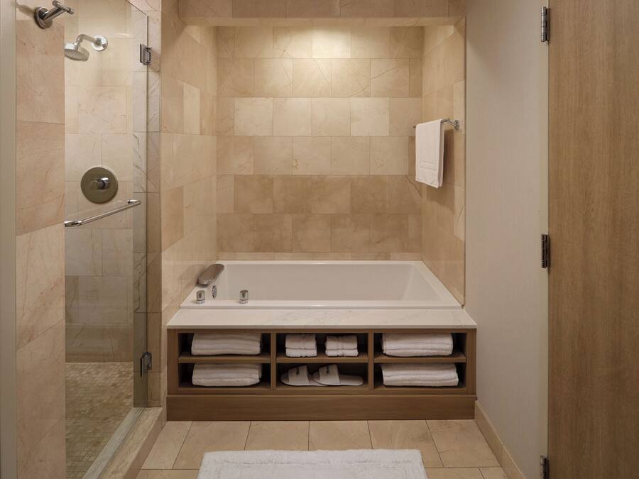 Une salle de bain moderne dotée d’une douche à l’italienne, d’une baignoire sur pieds et d’un porte-serviettes intégré.