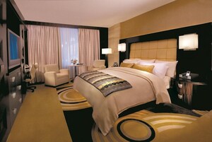 Una habitación de hotel con una cama grande, dos mesitas de noche, un escritorio, una silla y un televisor.