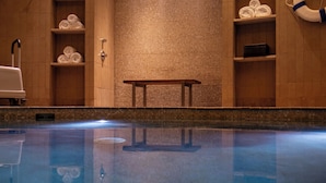 Ein Wellnessbereich mit Pool, einer Bank und Regalen mit Handtüchern.