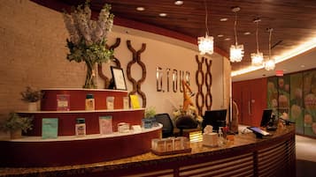 A reception desk with a wooden counter, a potted plant, and a wall with decorative elements.