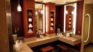 Ein modernes Badezimmer mit Granit-Arbeitsplatten, einem Holz-Waschtisch und einem großen Spiegel mit beleuchtetem Rahmen.