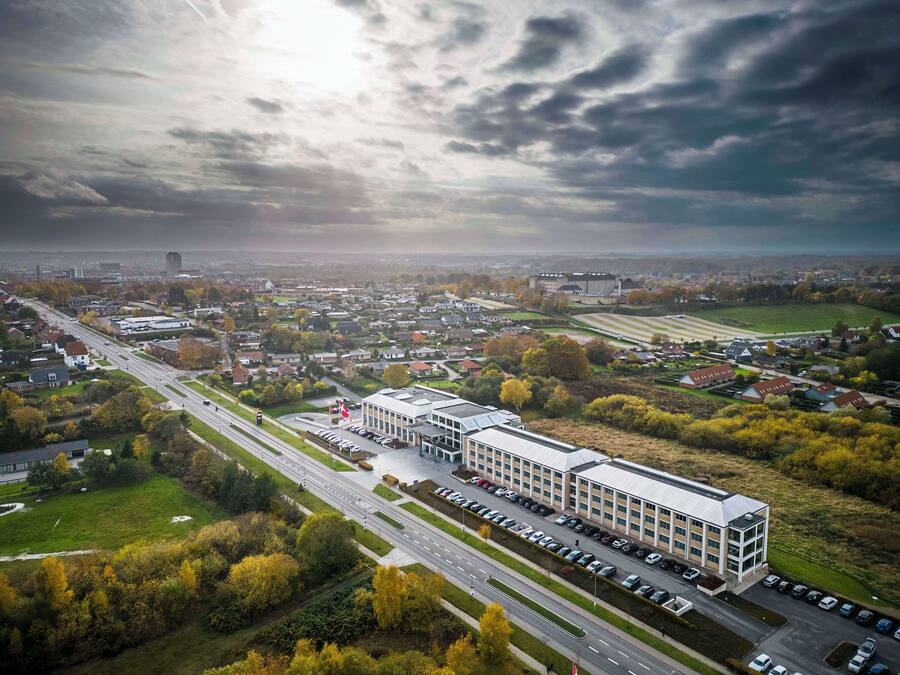 An aerial view of a modern building complex with multiple parking lots and a large road intersecting it.