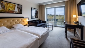 Una habitación de hotel con dos camas, un sofá, un escritorio y un balcón con vistas.