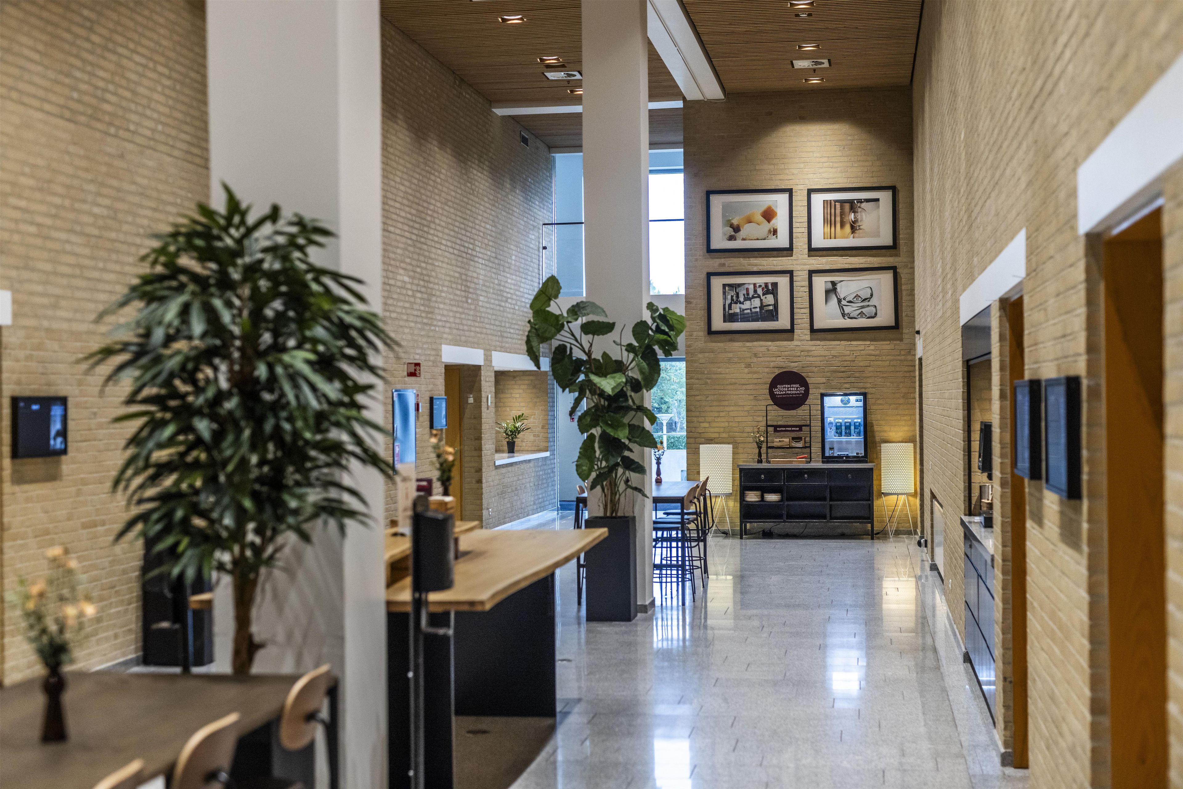 A spacious, modern interior with a high ceiling, brick walls, and a central open area with seating.