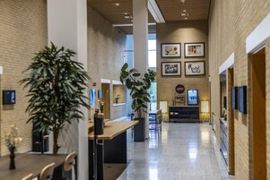 Un interior amplio y moderno con techo alto, paredes de ladrillo y un espacio central abierto con asientos.