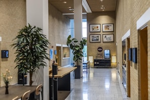 A spacious, modern interior with a high ceiling, brick walls, and a central open area with seating.
