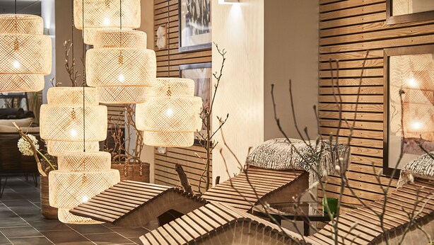 Un interior moderno con lámparas de mimbre escalonadas, sillones de madera y una pared de madera con un cuadro enmarcado.