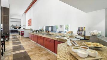 Un espace cuisine moderne doté d’un plan de travail en granit, de meubles rouges, ainsi que de divers aliments et appareils électroménagers.