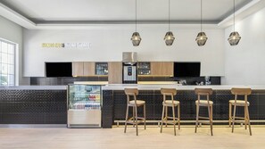 A modern kitchen with a built-in refrigerator, a microwave, and a coffee machine. There are four wooden bar stools and a large window providing natural light. - Fiesta Inn Express Ciudad Obregón (Cajeme)