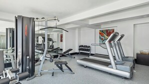 A gym with various exercise equipment including a treadmill, weight machines, and dumbbells. - Fiesta Inn Express Ciudad Obregón (Cajeme)