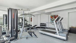 A gym with various exercise equipment including a treadmill, weight machines, and dumbbells. - Fiesta Inn Express Ciudad Obregón (Cajeme)