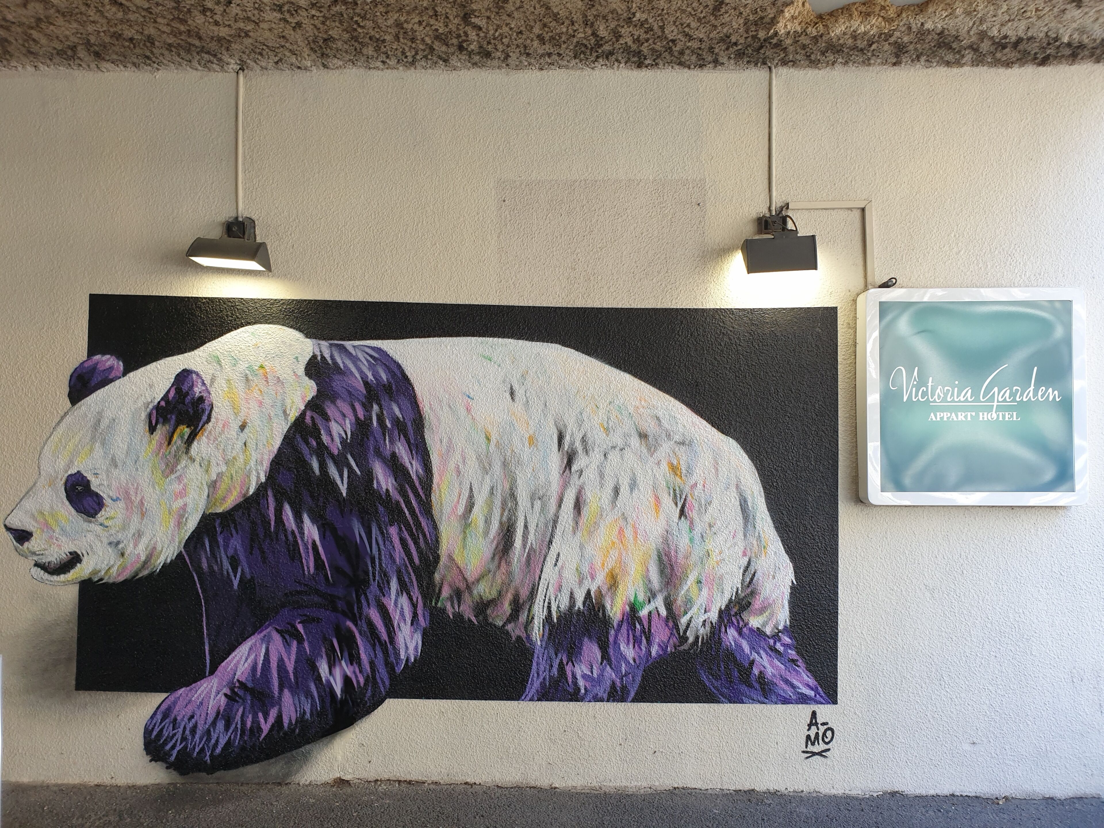 A large panda mural on a wall, with two pendant lights above it.