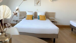 Habitación de hotel moderna con una cama grande, dos mesitas de noche, una lámpara de noche y una obra de arte colgada en la pared.