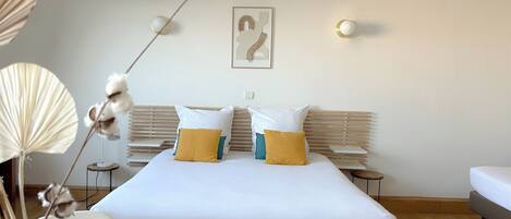 Habitación de hotel moderna con una cama grande, dos mesitas de noche, una lámpara de noche y una obra de arte colgada en la pared.