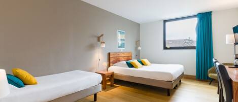 Una habitación de hotel con dos camas individuales, un escritorio de madera, una silla y una ventana con cortinas.