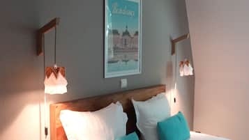 Una cama bien tendida con almohadas blancas y turquesas, un cabecero de madera y un cuadro en la pared.