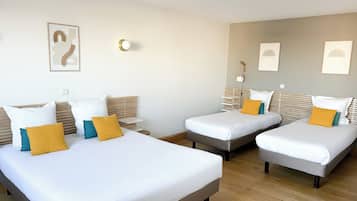 A hotel room with two single beds, a wooden floor, and a neutral color scheme.