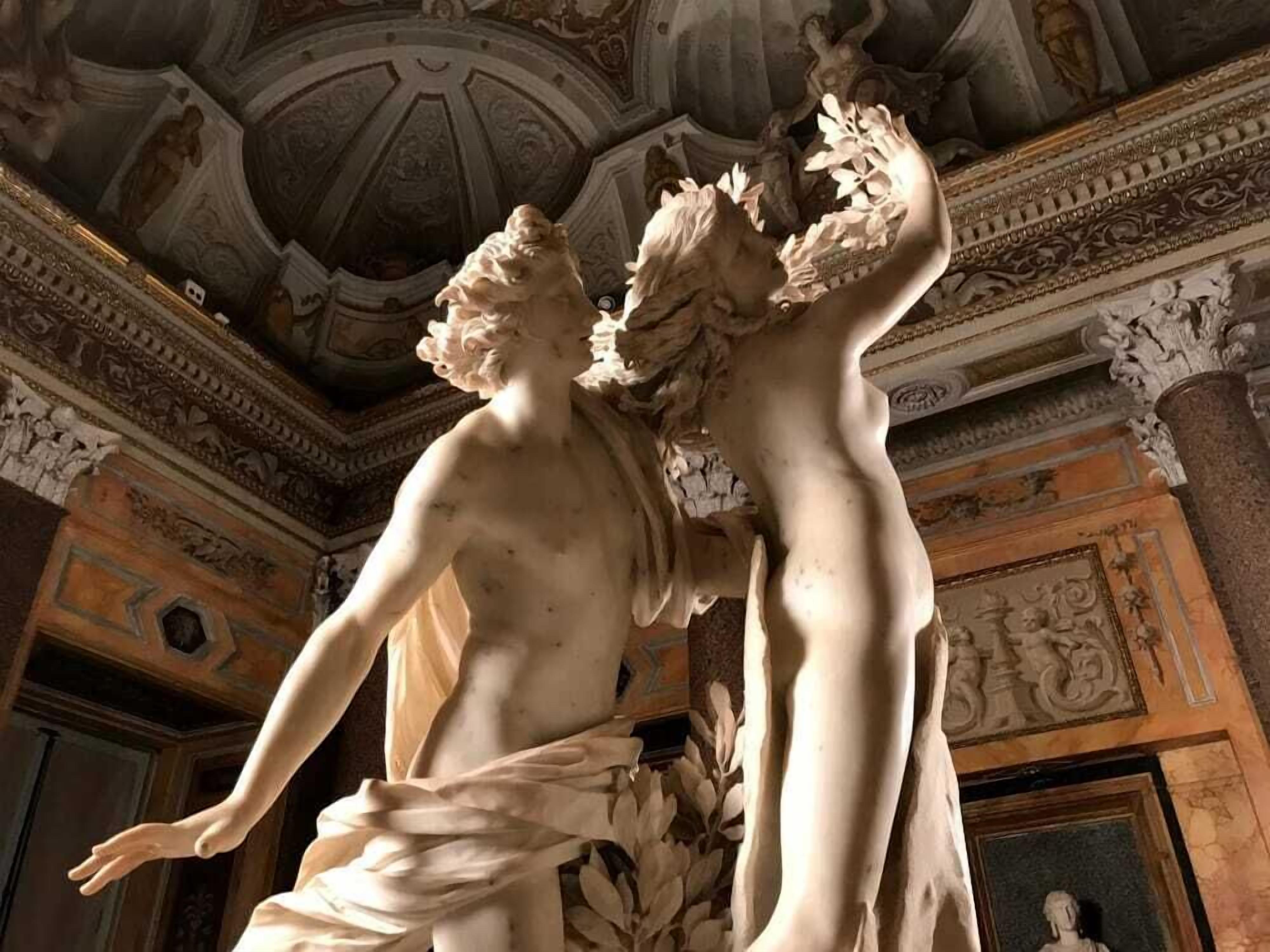 Eine Marmorstatue von zwei Figuren in einer klassischen Architektur mit aufwändiger Decke und detailreichen Wandfriesen.