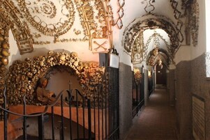 Un pasillo con decoraciones ornamentales en las paredes, una escalera con una persona sentada y una barandilla de metal.