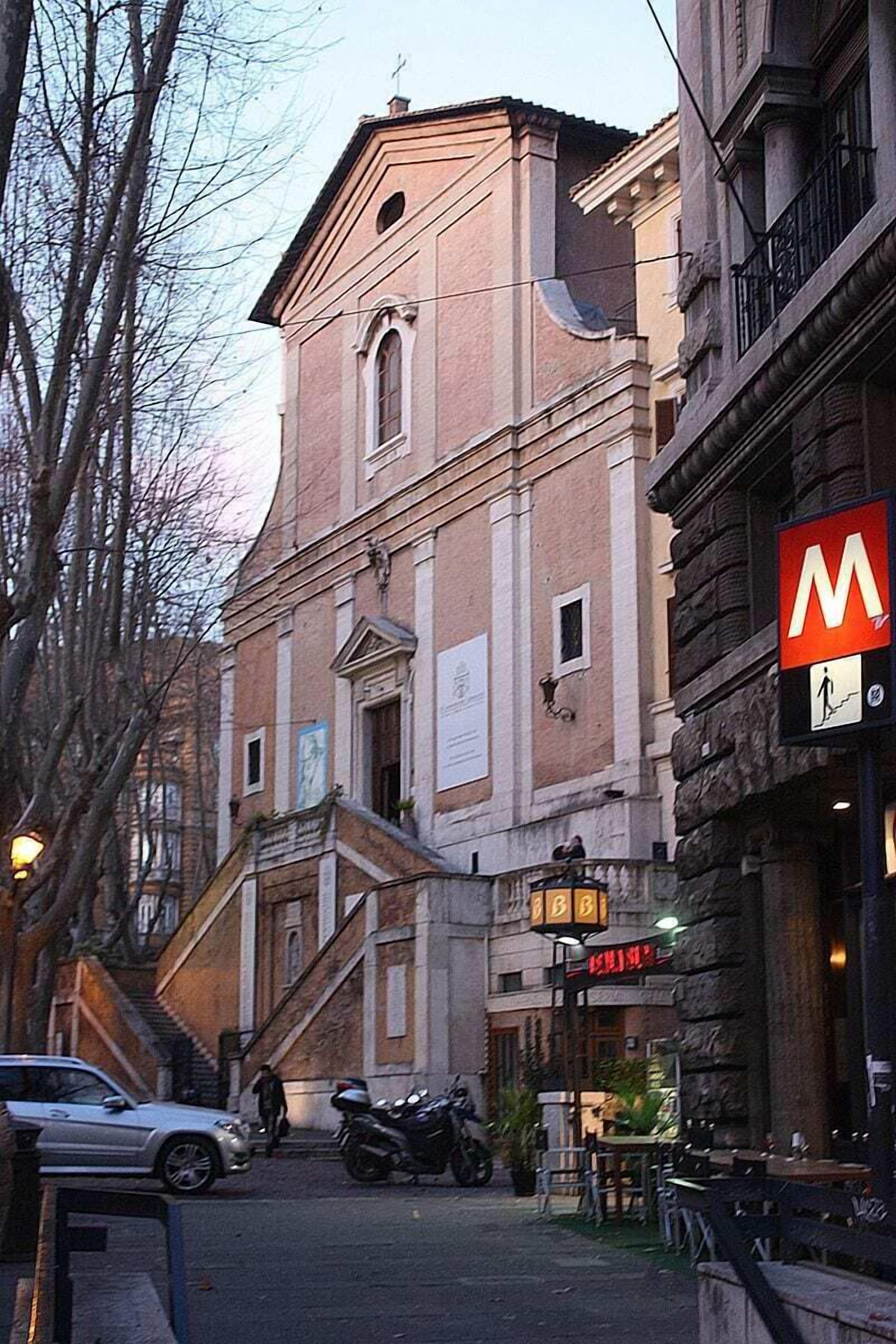 A building with a prominent 'M' sign, a staircase leading to an upper level, and a parked motorcycle.