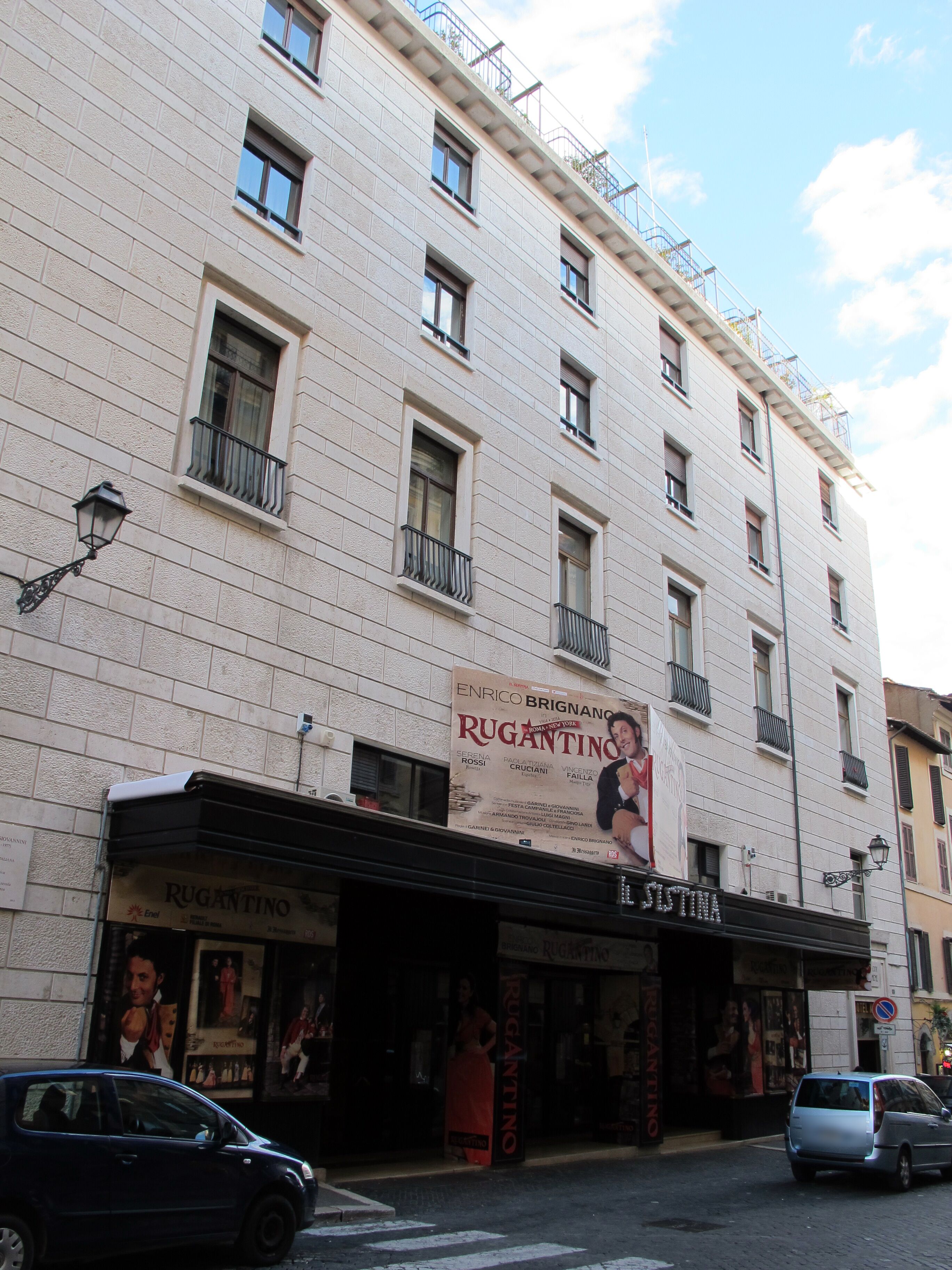 A multi-story building with a theater entrance, featuring a large poster advertising a play.