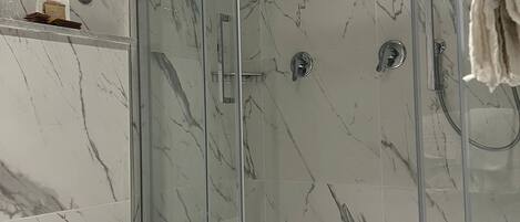 A modern bathroom with a glass-enclosed shower, a toilet, and a large sink.