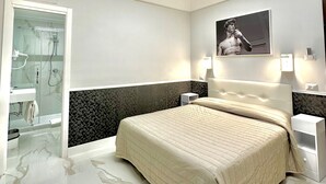 A modern bedroom with a large bed, a glass shower enclosure, and a marble floor. - Hotel Garda (Rome)