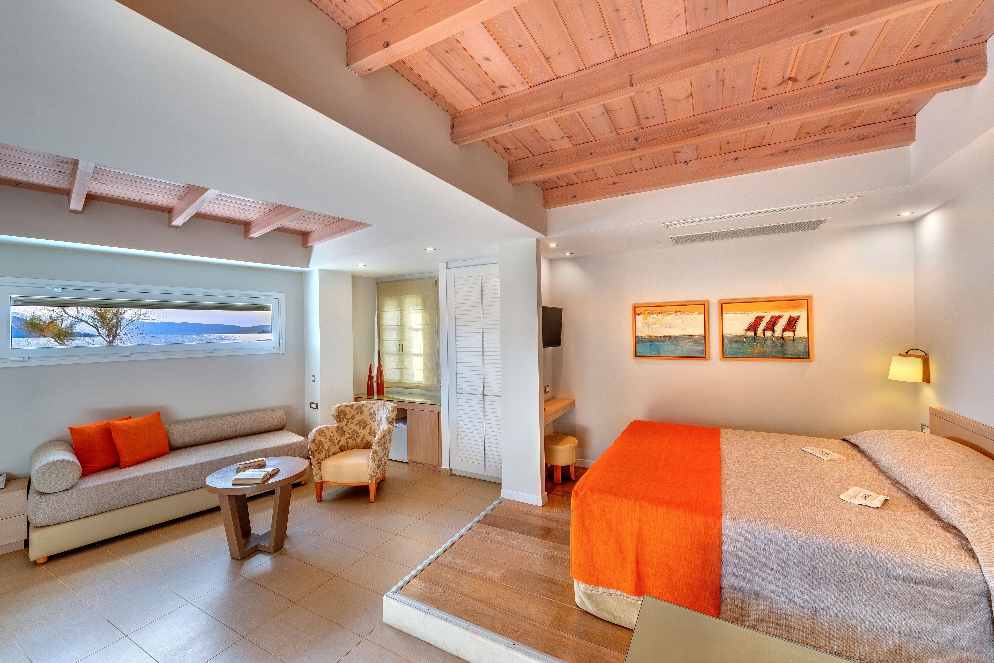 A modern hotel room with a sofa, armchair, and bed.