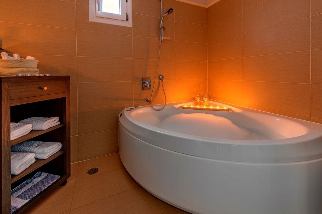 A modern bathroom with a large bathtub, a wooden vanity with towels, and a shower.