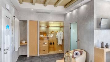 A modern bathroom with a shower, a vanity with a mirror, and a wooden cabinet with towels and toiletries.