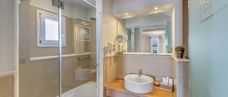 A modern bathroom with a glass-enclosed shower, a sink with a mirror, and a wooden vanity.