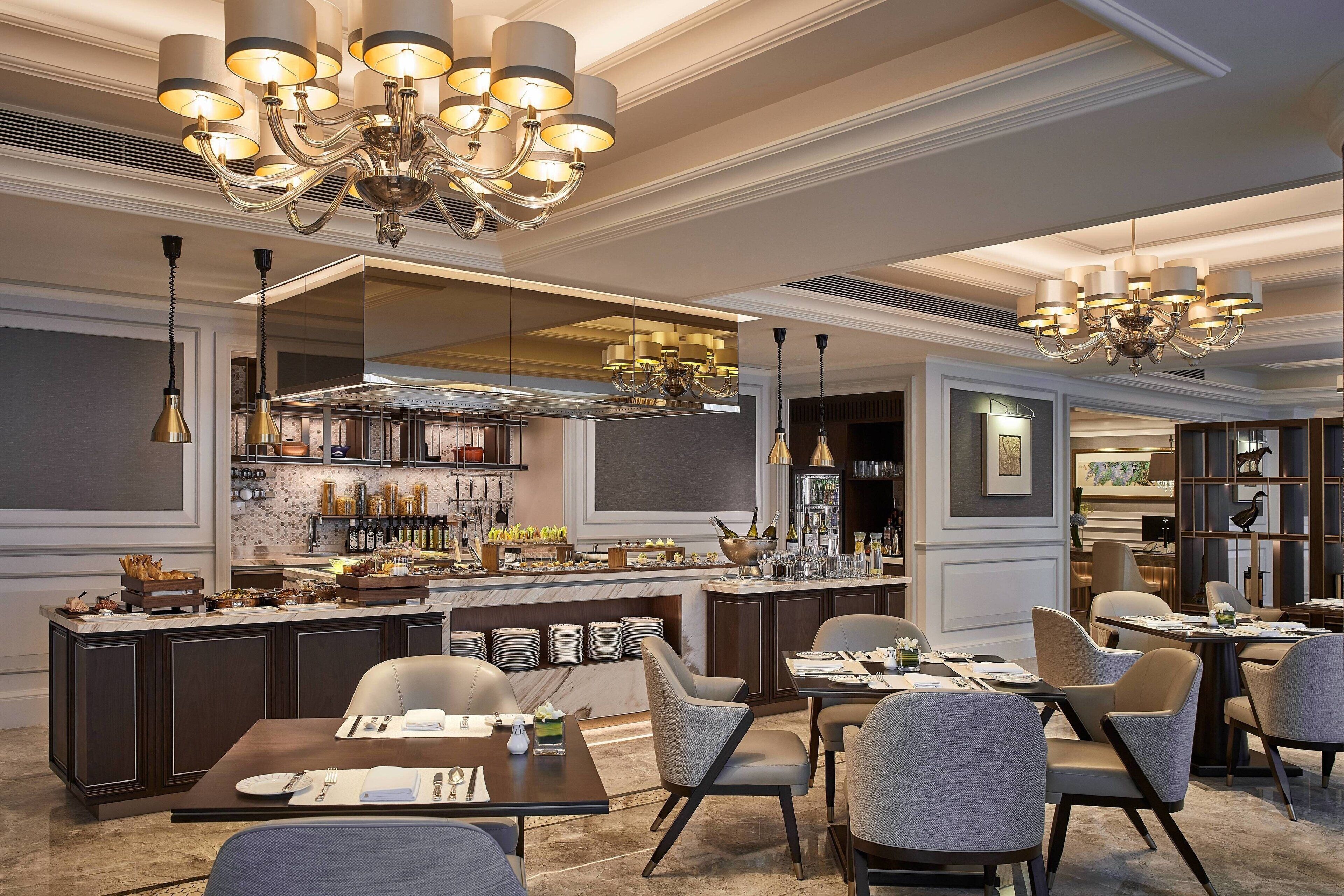 Un restaurante moderno con barra central, varias zonas de estar y elegantes candelabros.