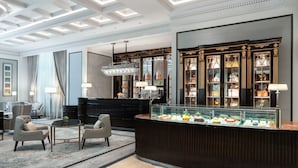A lobby with a reception desk, seating area, and a display case with items. - The Ritz-Carlton, Guangzhou (Guangzhou)