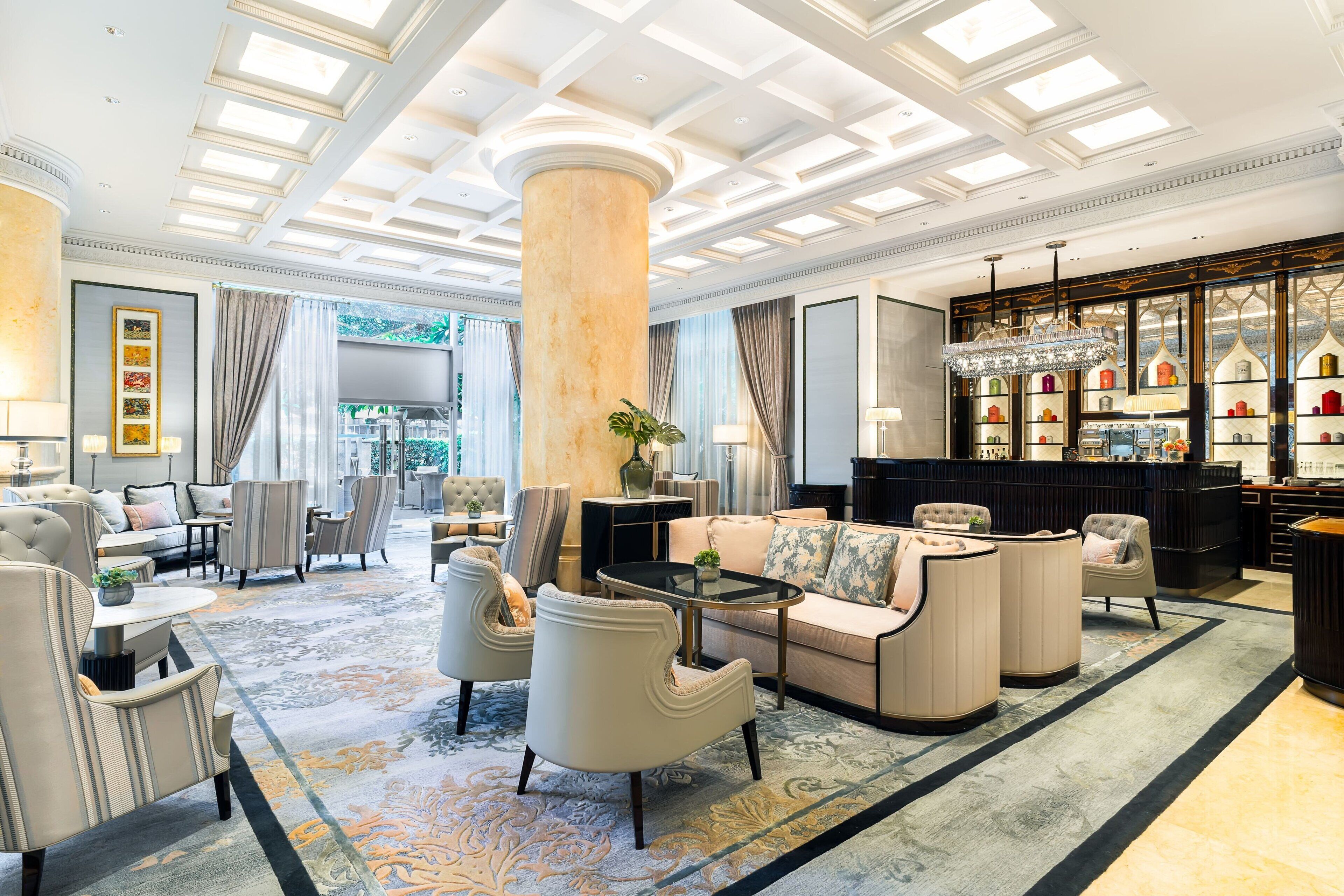 A spacious lobby with a large central column, seating area, and a bar with shelves of bottles.