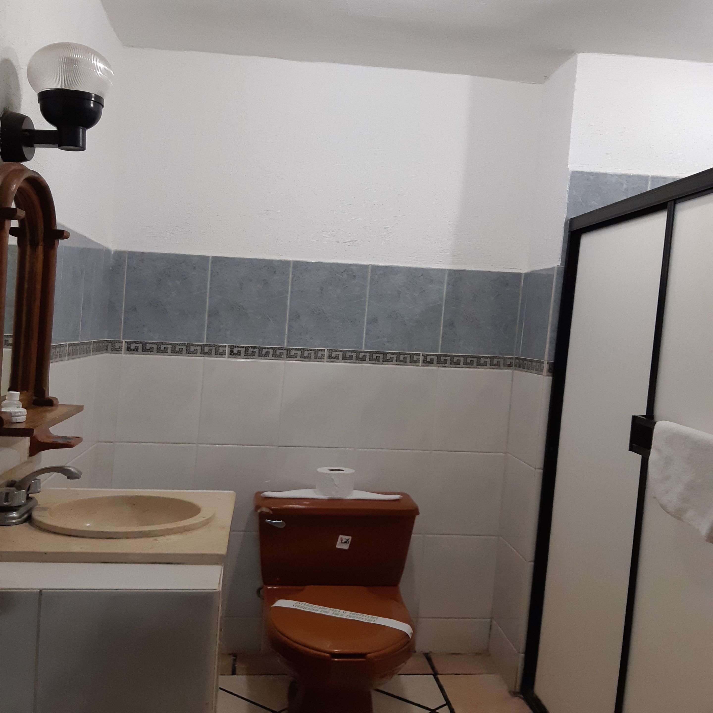 A bathroom with a sink, toilet, and a mirror with lights.
