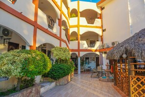 Un patio de varios niveles con un espacio central abierto, rodeado de balcones y zonas de estar cubiertas.